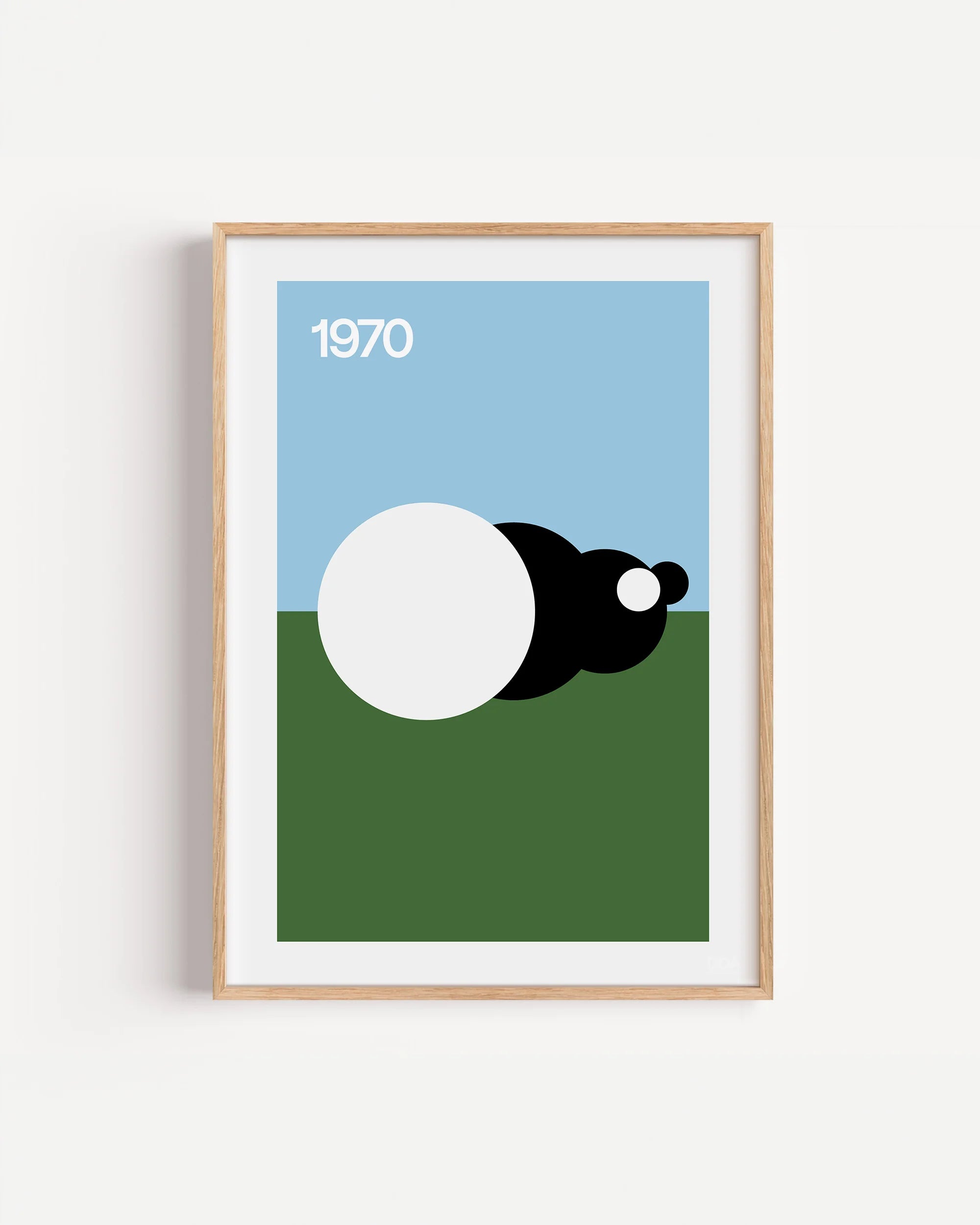 Poster 1970 di DDA in cornice rovere su parete bianca: cielo azzurro, prato verde e una fila di cerchi bianchi e neri.