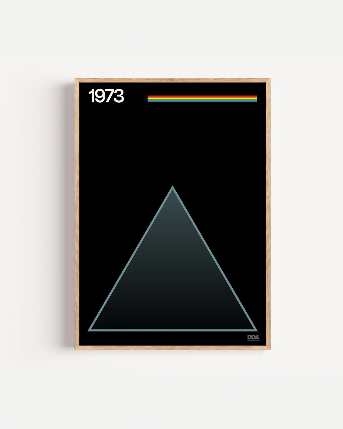 Poster 1973 di DDA in cornice rovere su parete bianca: un triangolo che sfuma nel nero e un filo di colori in alto.