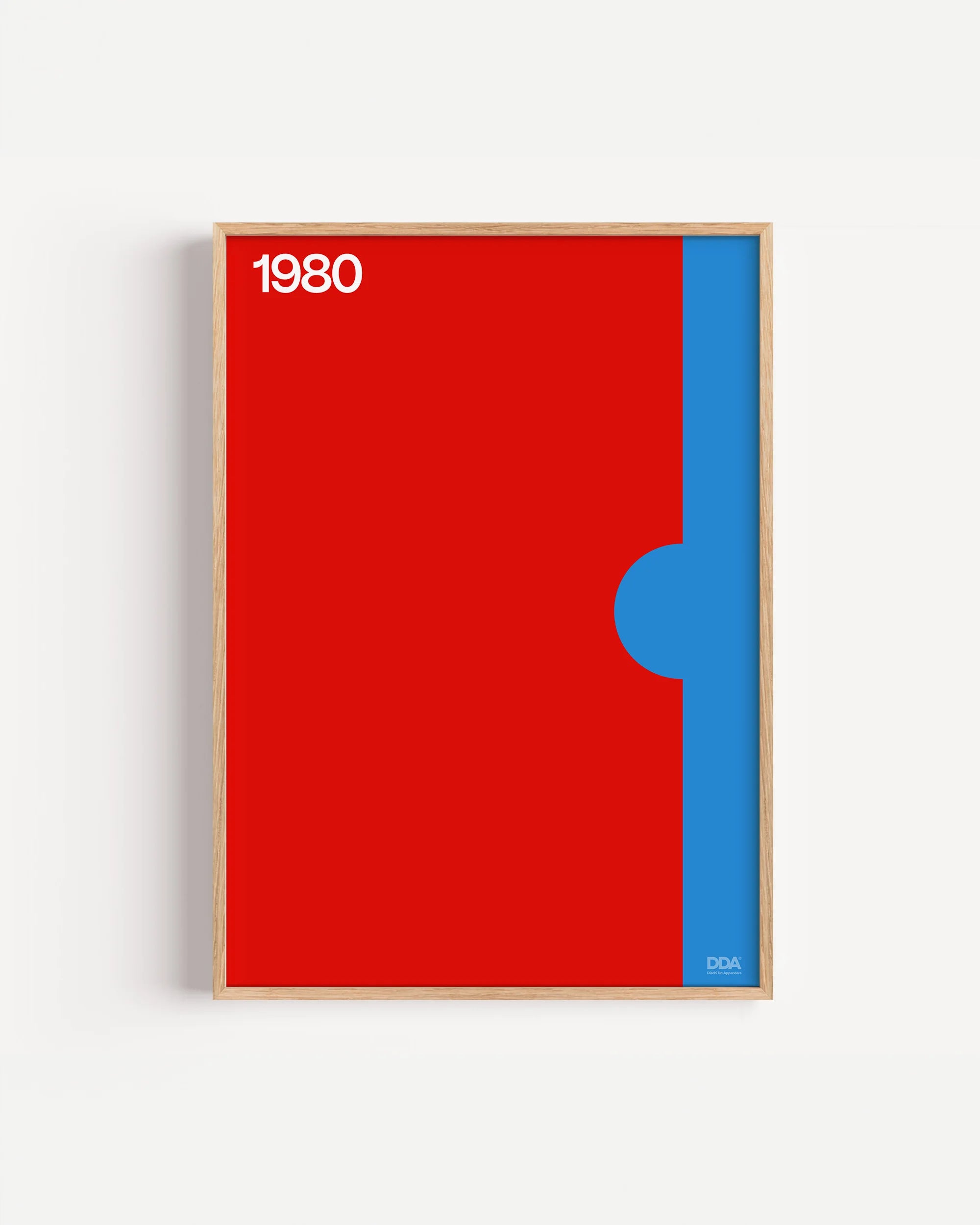 Poster 1980 di DDA in cornice rovere su parete bianca: rosso pieno con una fascia azzurra verticale e un semicerchio che la morde.
