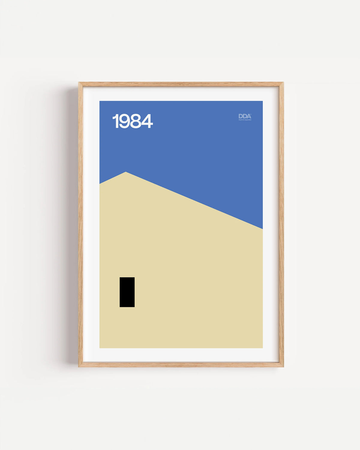 Poster 1984 di DDA in cornice rovere su parete bianca: un cielo blu, una parete color sabbia e una piccola porta nera.