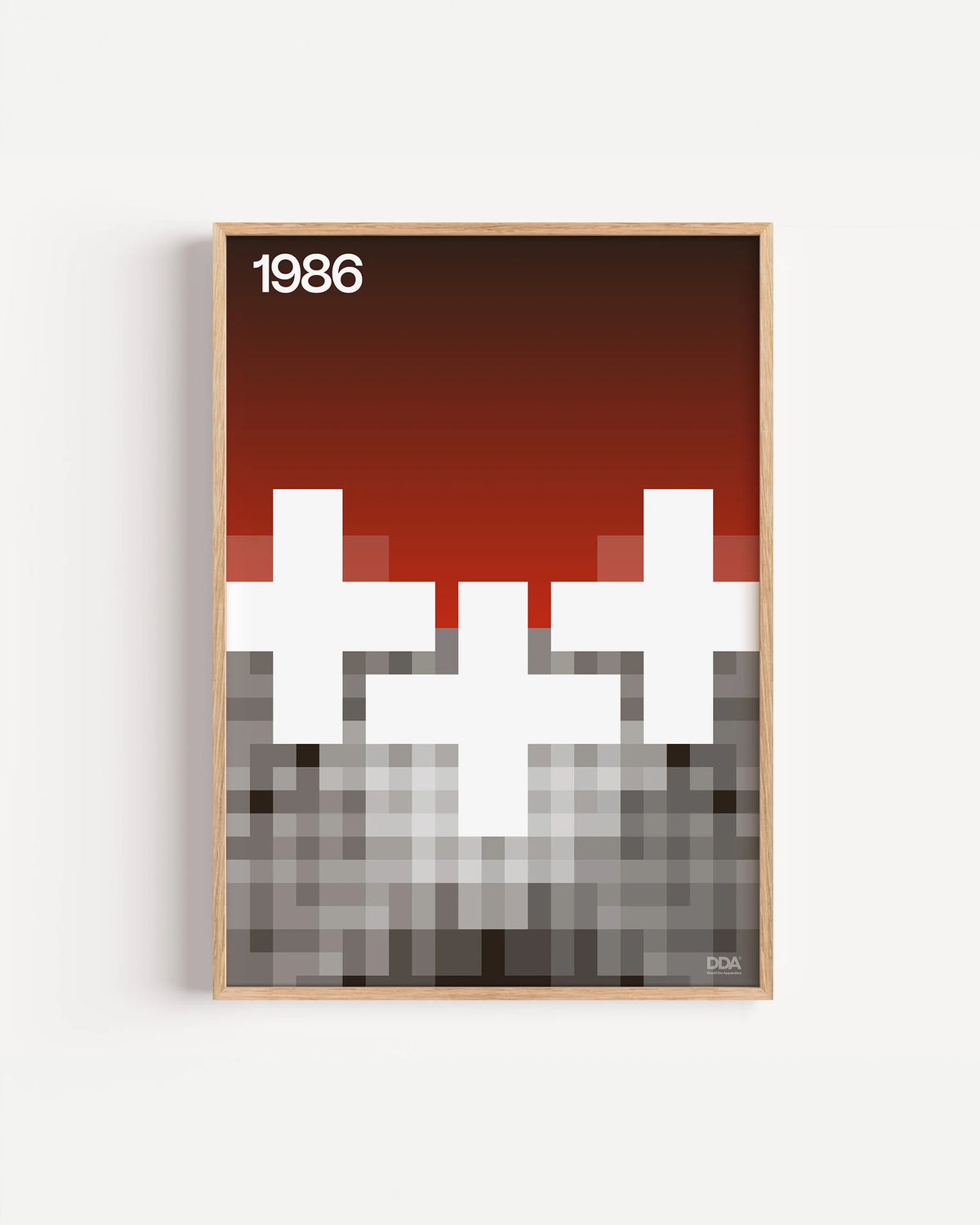 Poster 1986 di DDA in cornice rovere su parete bianca: croci bianche su un cielo che sfuma dal rosso al nero, con una base a pixel.