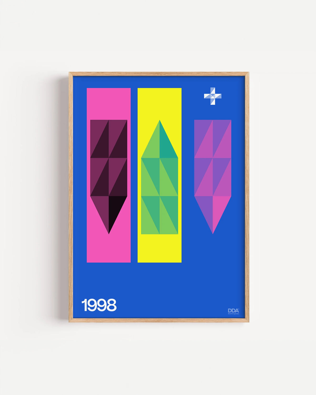 Poster 1998 di DDA in cornice rovere su parete bianca: tre colonne rosa, gialla e viola con forme a cristallo, su fondo blu.