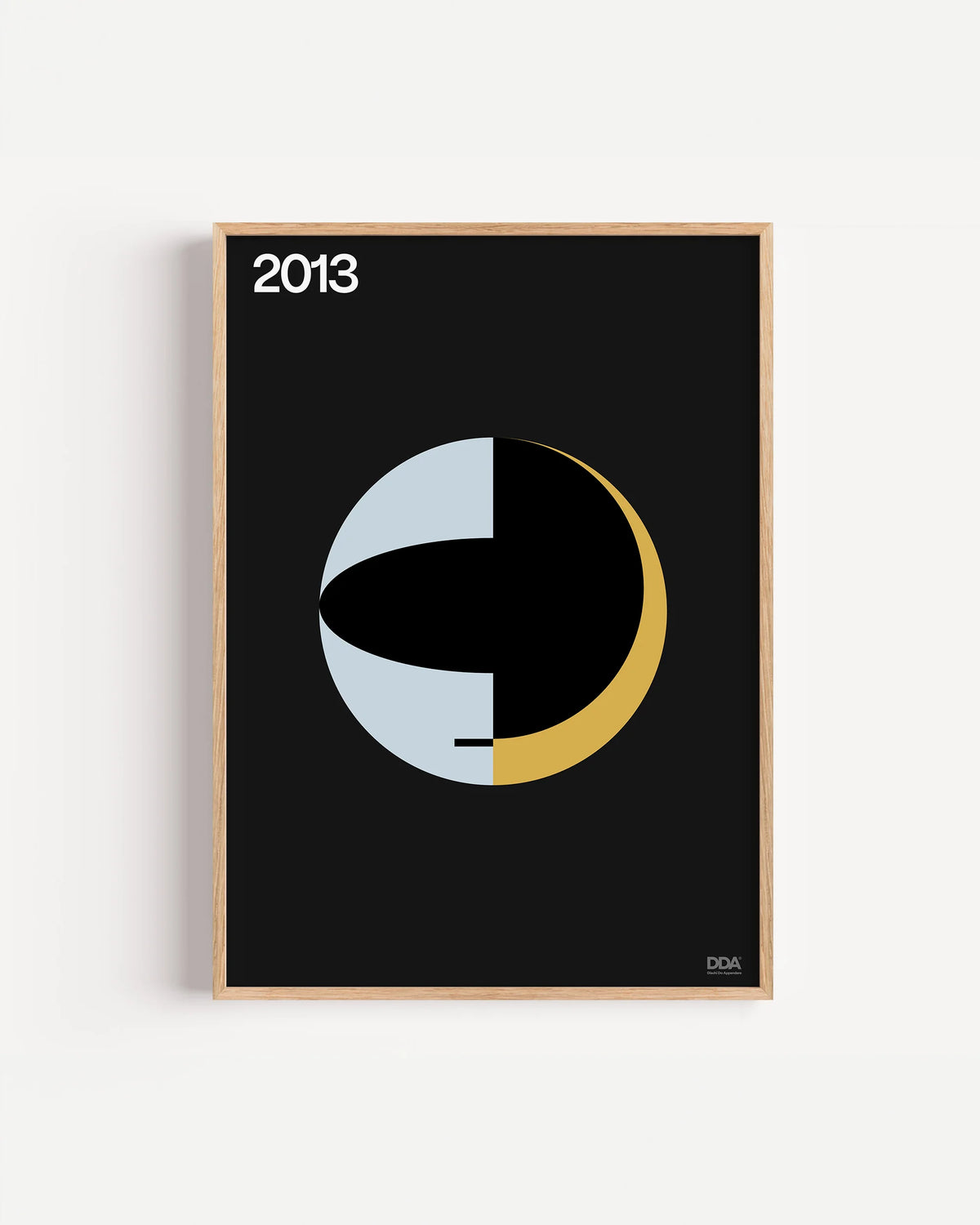 Poster 2013 di DDA in cornice rovere su parete bianca: un cerchio diviso tra azzurro, nero e oro.